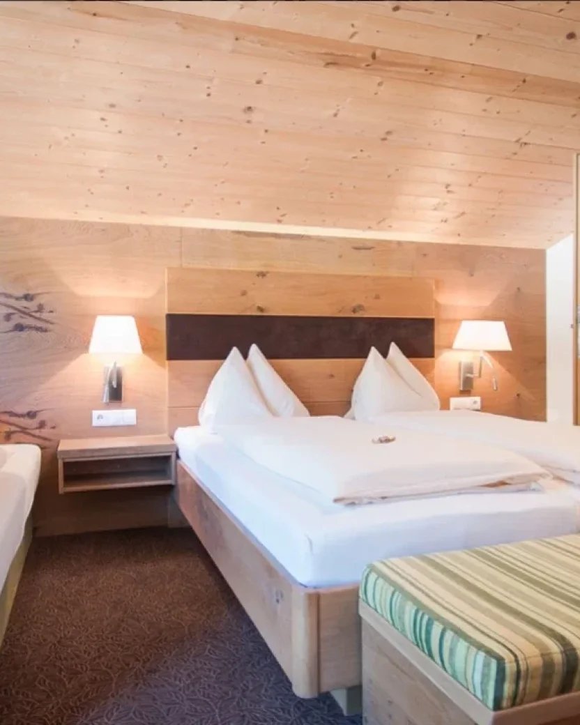 Ruime hotelkamer met drie bedden en een eigen badkamer.