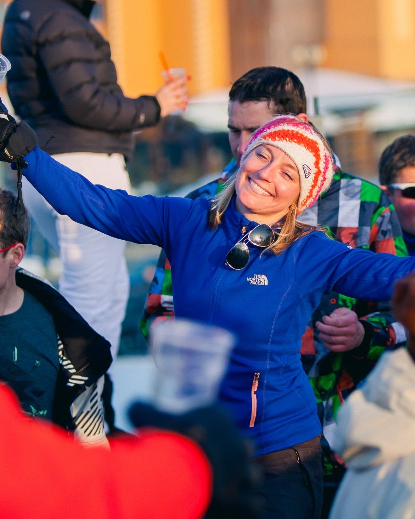 Een groep wintersporters geniet samen van een drankje in de zon tijdens de après-ski.