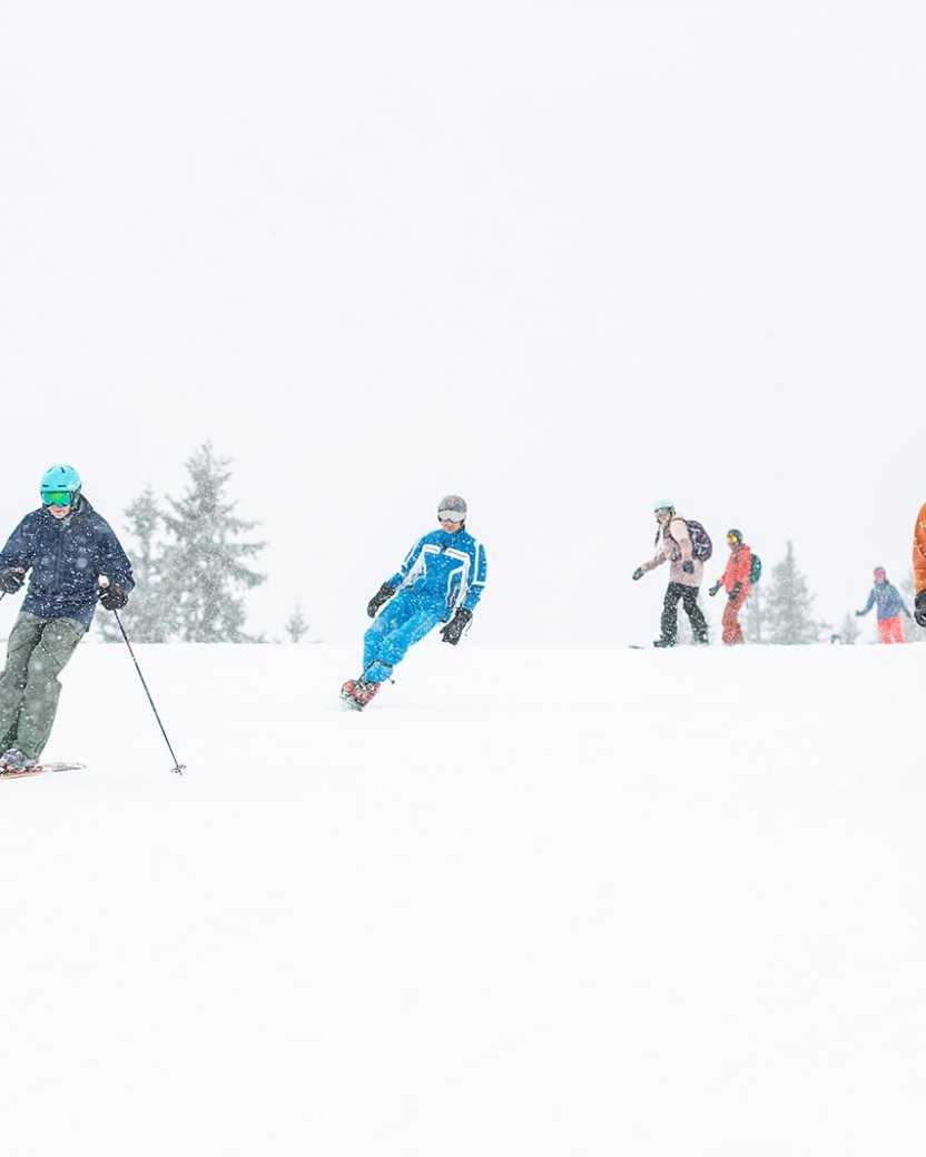 Skiërs op de piste tijdens een sneeuwbui.