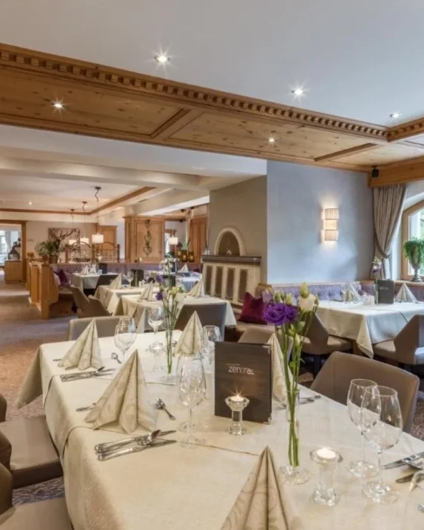 Sfeervol hotelrestaurant met gedekte tafels voor ontbijt en diner.