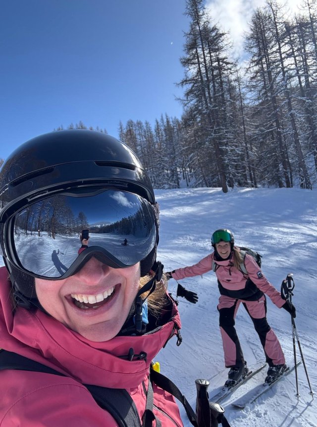Twee wintersporters poseren enthousiast voor de foto op de piste.