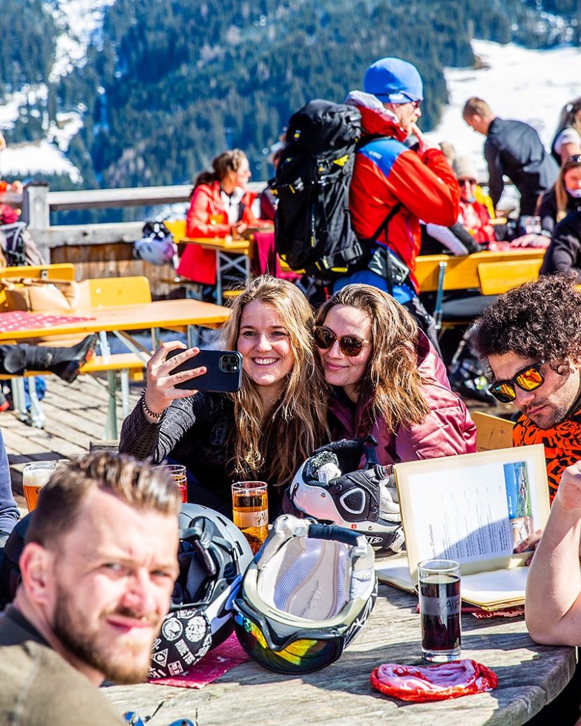 Wintersporters op het zonnige terras met besneeuwde bergen op het achtergrond.