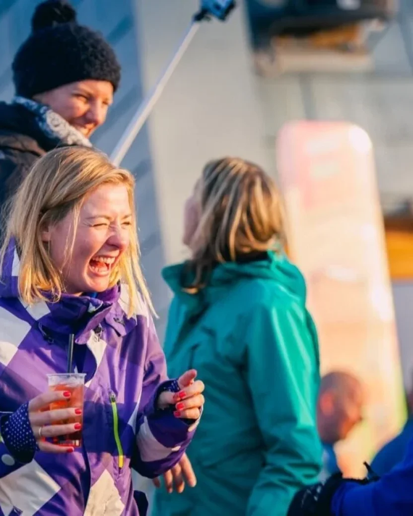 Wintersporters lachen met een drankje in de hand tijdens de après-ski.