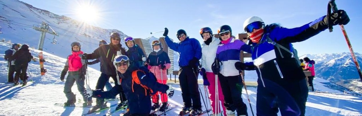 Wintersporters lachen voor de groepsfoto in de zon op de piste.