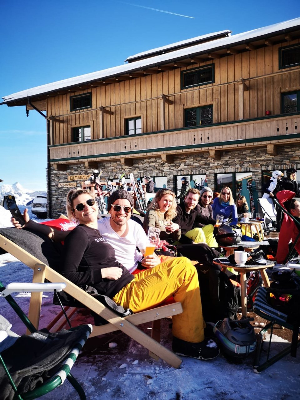 Wintersporters proosten samen op een zonnig terras aan de piste.