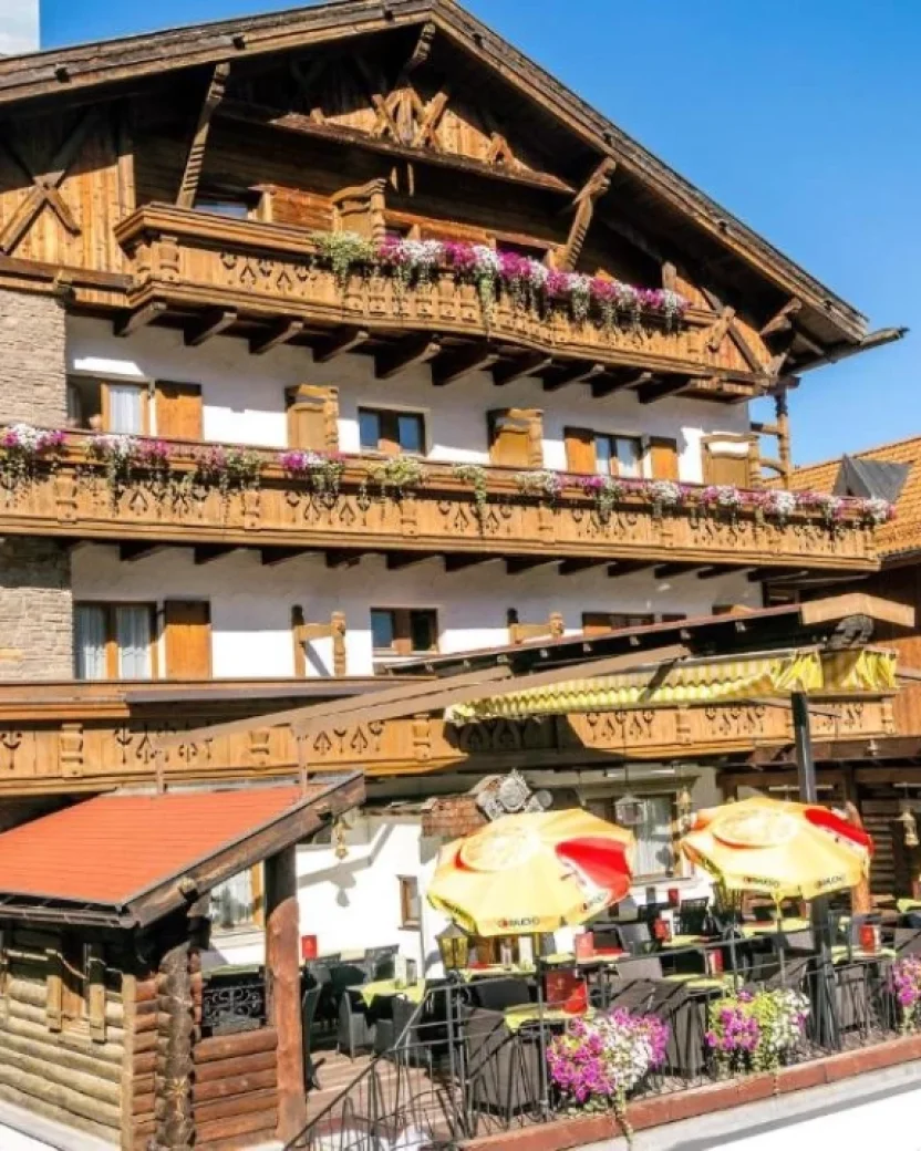 Traditioneel berghotel met houten balkons en zonnig terras.