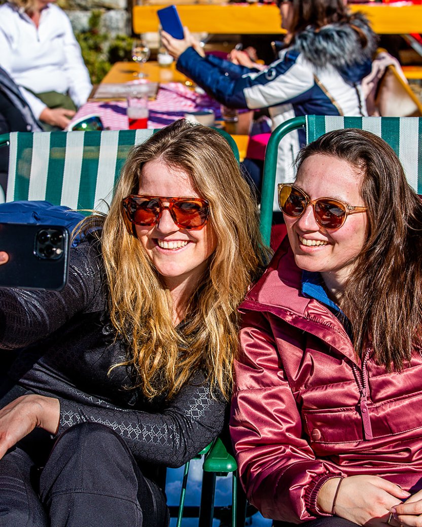 Twee wintersporters maken een selfie op het zonnige terras.