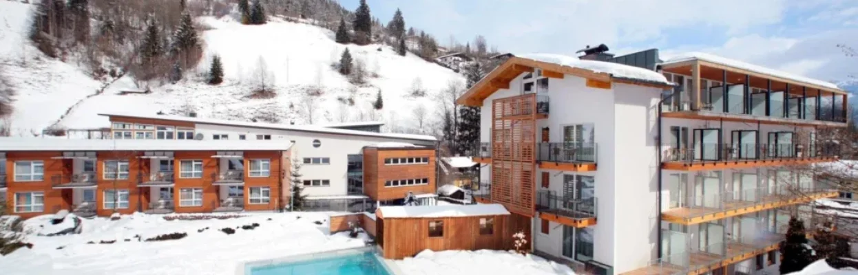 Wintersporthotel met verwarmd buitenzwembad in een besneeuwd berglandschap.