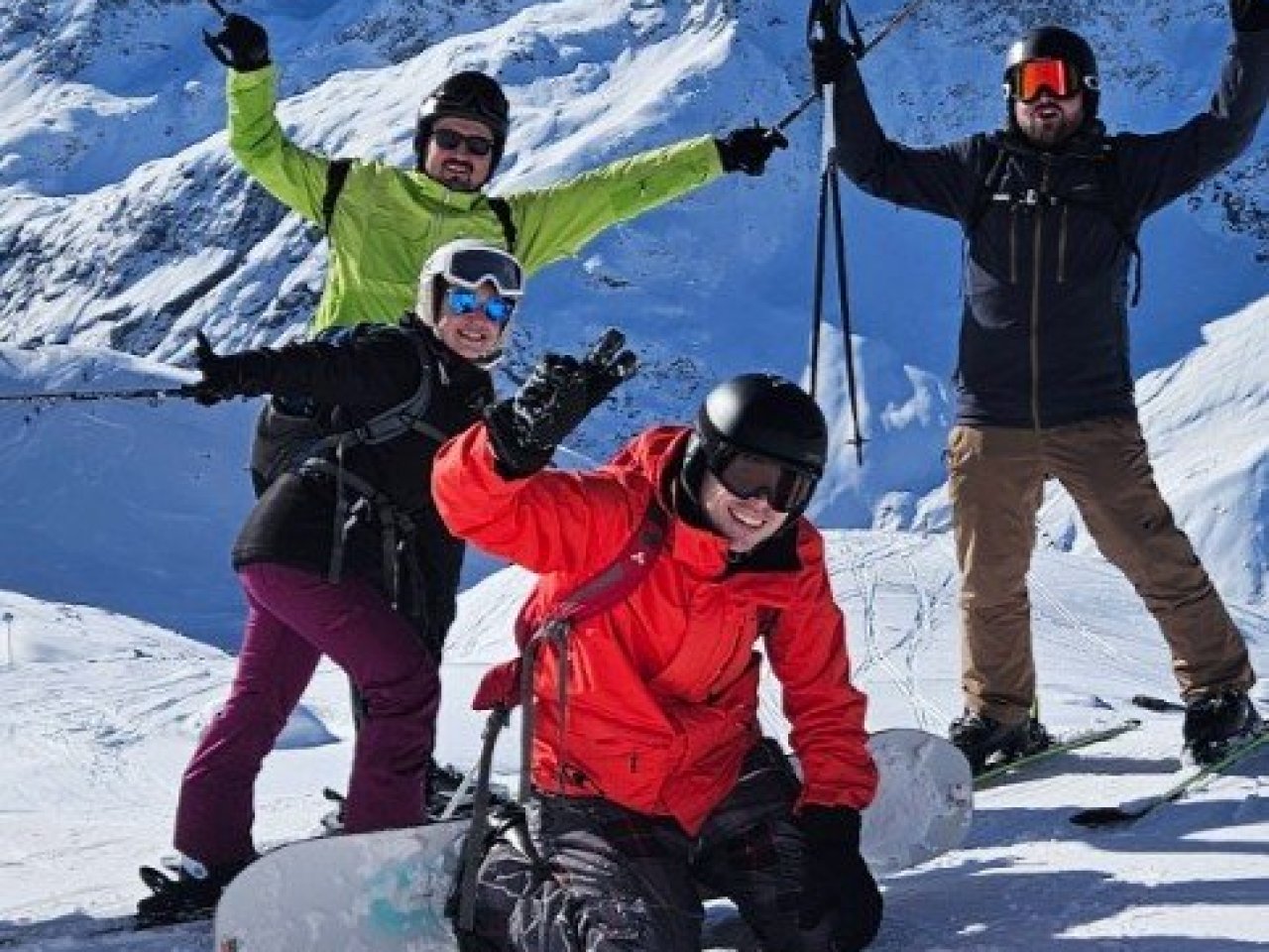 Wintersporters poseren voor de foto in de zon bovenaan de piste.