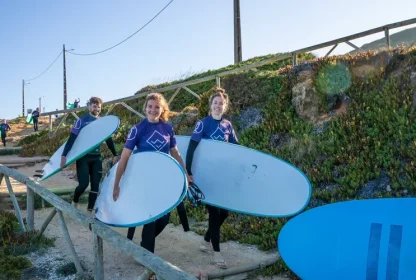 Reisgenoten lopen met surfplanken onder hun arm naar het strand.