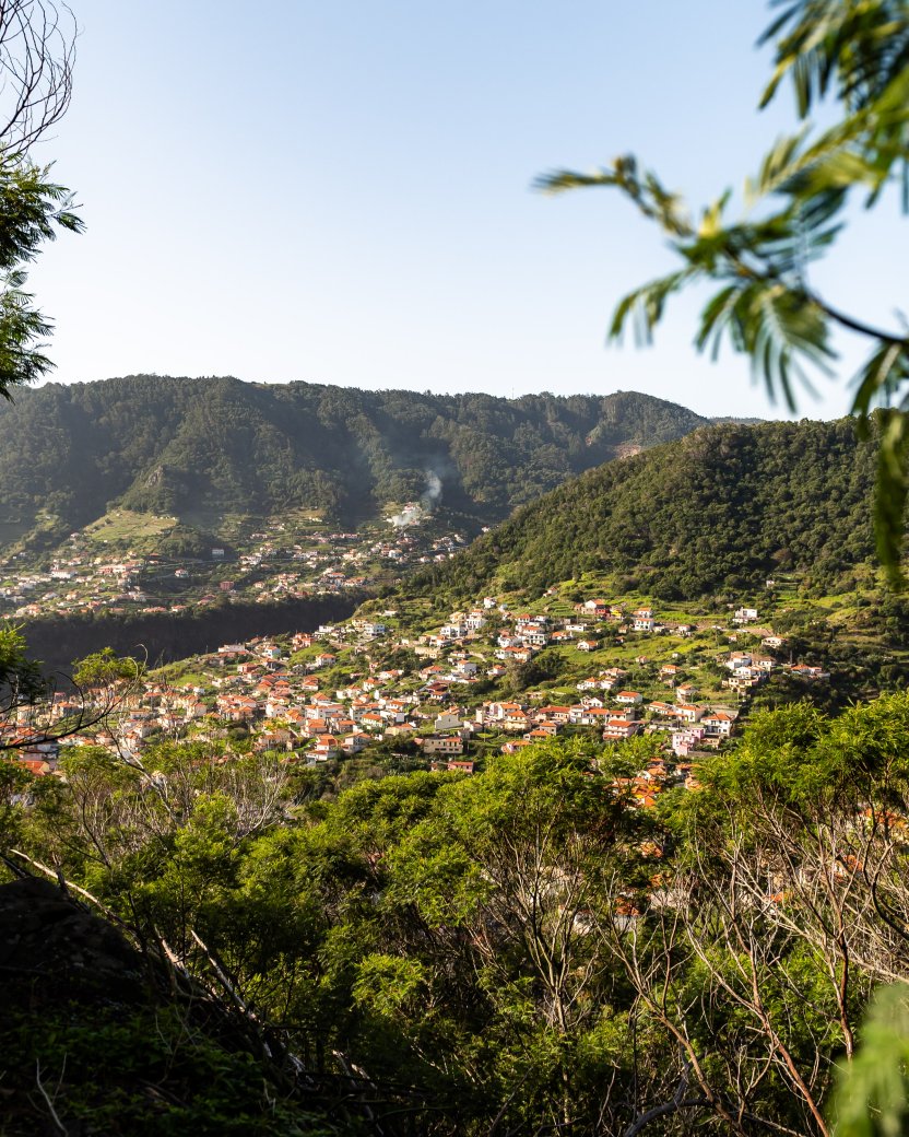 Uitzicht over een groen bergdorp met huizen verspreid over de heuvels.