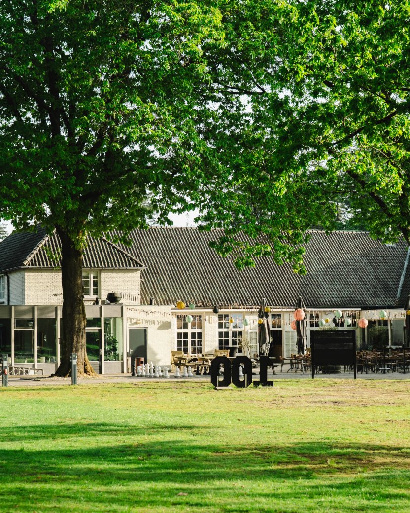 VillaVibes-locatie met terras en groot grasveld in een groene, bosrijke omgeving.