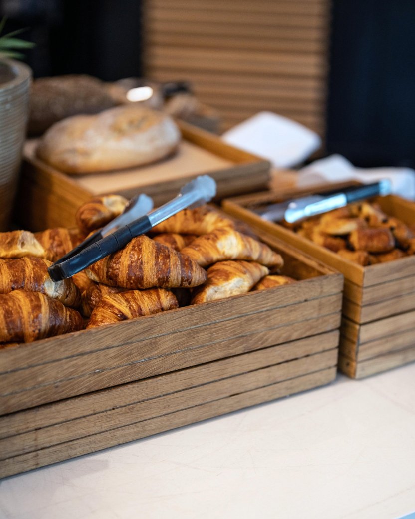 Ontbijtbuffet met croissants, broodjes en andere verse ontbijtproducten.