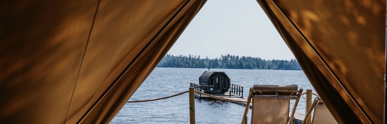 Uitzicht vanaf de tent op de steiger en de sauna op het water.