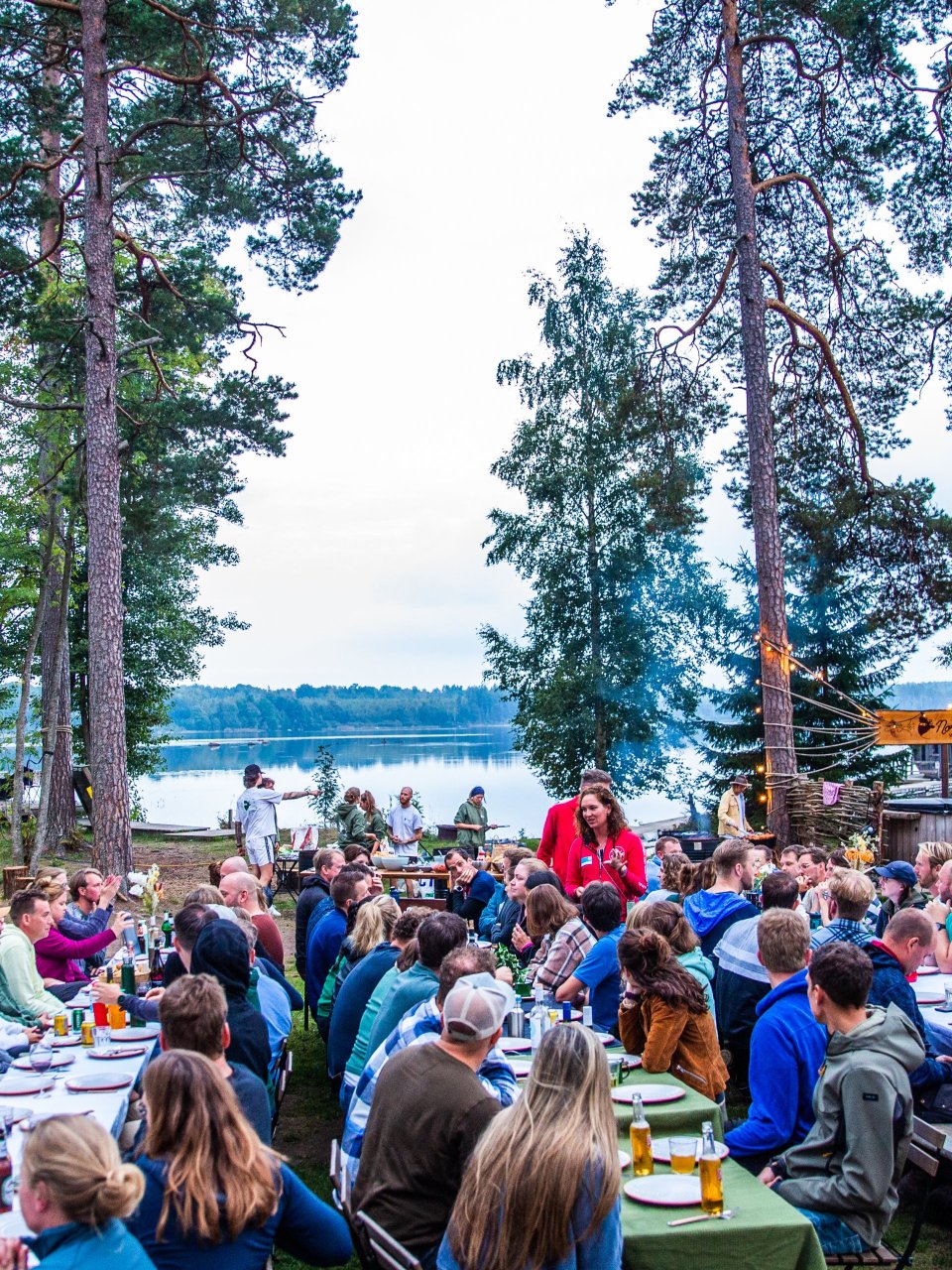 Reisgenoten dineren aan lange tafels buiten naast het meer.