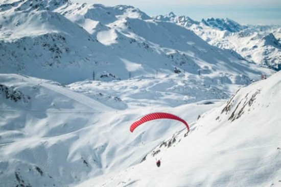 Paraglider over de besneeuwde bergen in Sankt Anton.