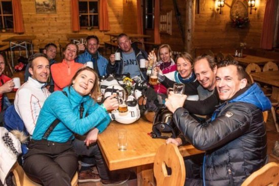 Wintersporters proosten samen met een drankje tijdens een borrel in een restaurant aan de piste.