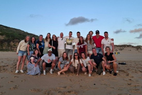 Groep reisgenoten poseert voor de foto op het strand in Ericeira.