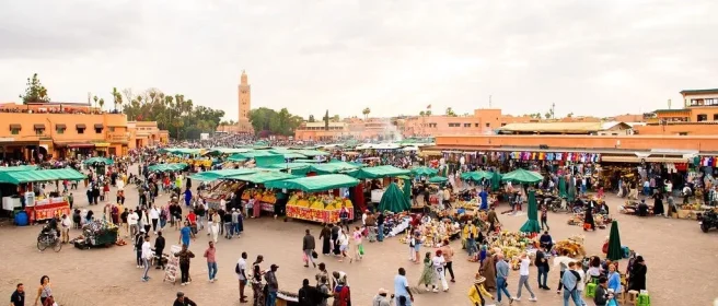 Druk marktplein in Marokko met veel kraampjes.