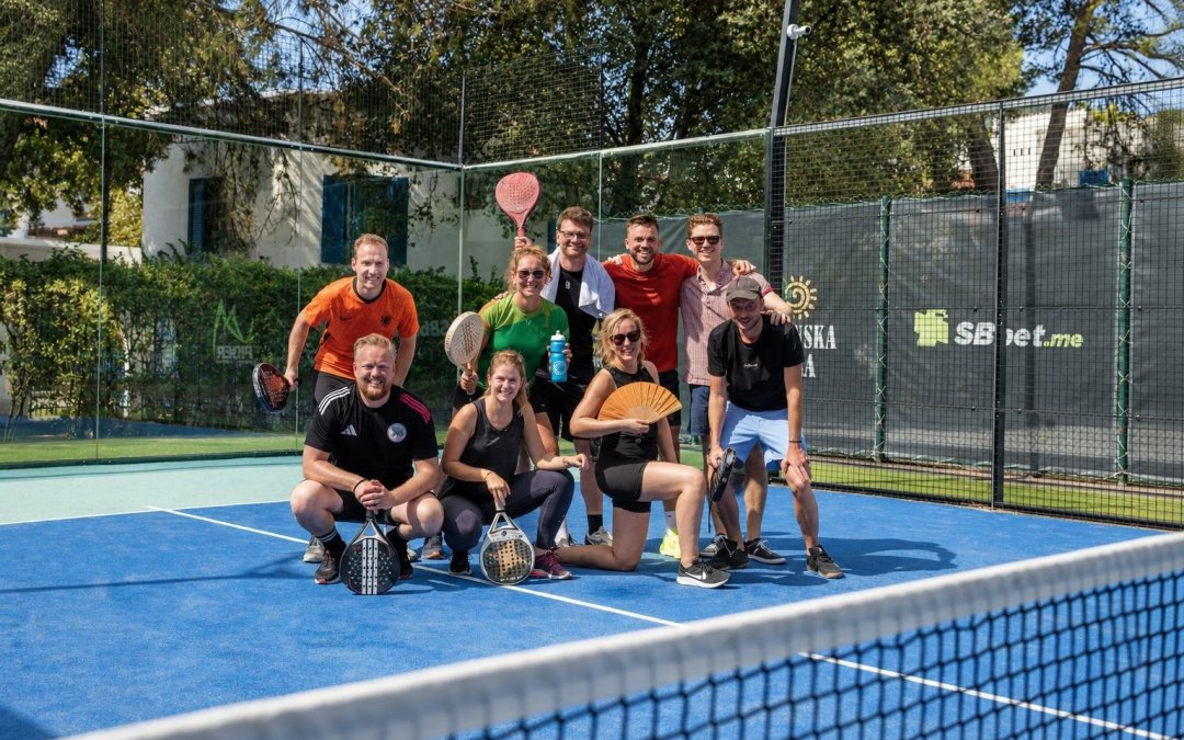 Groep padellers poseert voor de foto op de padelbaan.