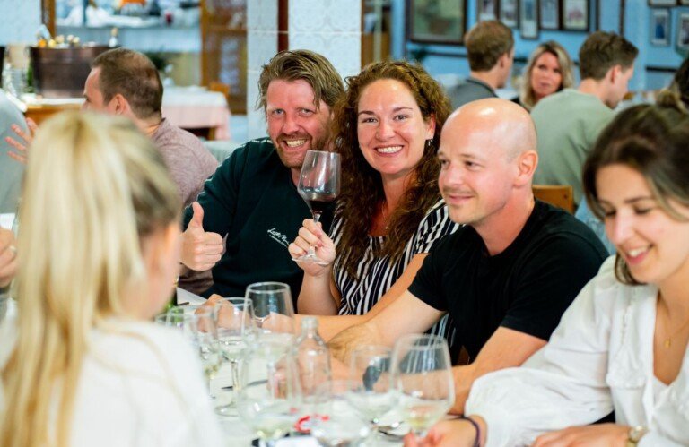 Reisgenoten zitten aan een lange tafel voor het diner.