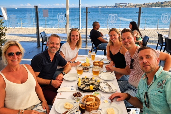 Reisgenoten lunchen op het terras aan zee.