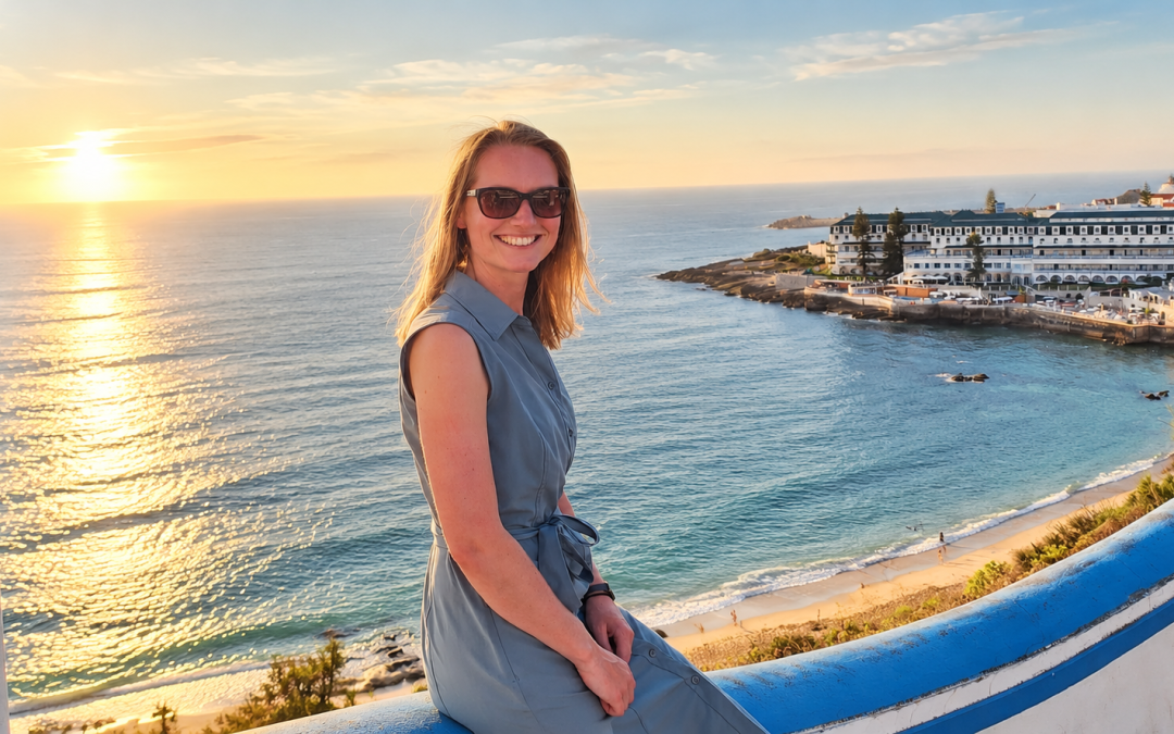 Surfer Femke poseert bij zonsondergang met uitzicht op de kust.