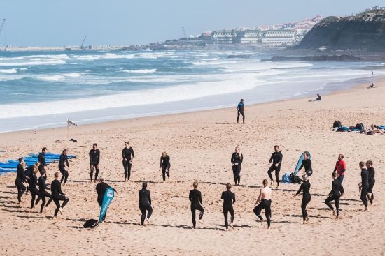Groep surfers doet een warming up op het strand in Ericeira.