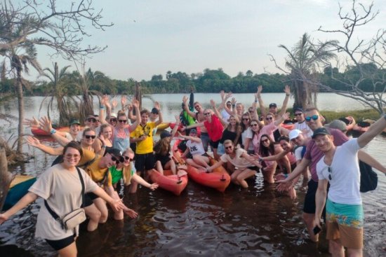 Groep reisgenoten poseert in het water tijdens de kanotocht in Gambia.