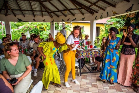 Reisgenoten eten en kletsen met locals in Gambia.