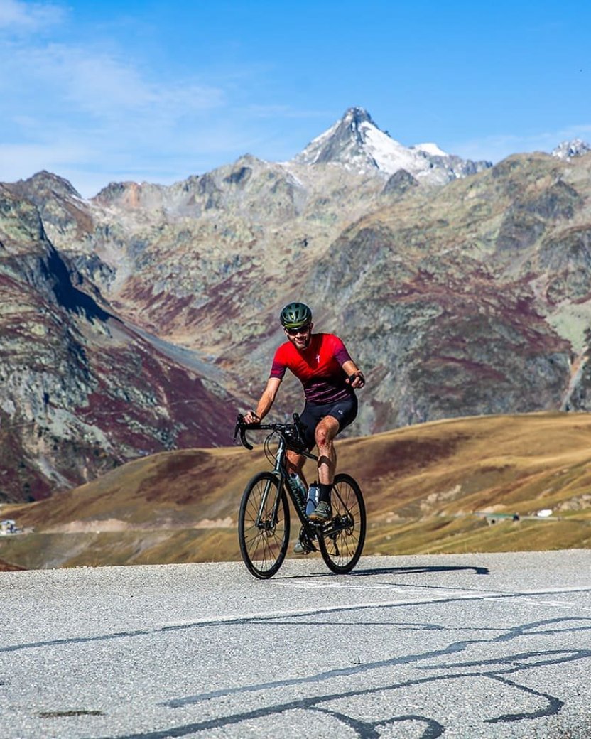 Reisgenoot op de fiets over de weg met bergen op het achtergrond.
