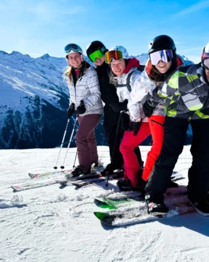 Wintersporters poseren voor de foto bovenaan de piste.