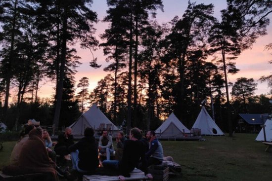 Reisgenoten ontspannen bij het kampvuur op de glamping tijdens zonsondergang.