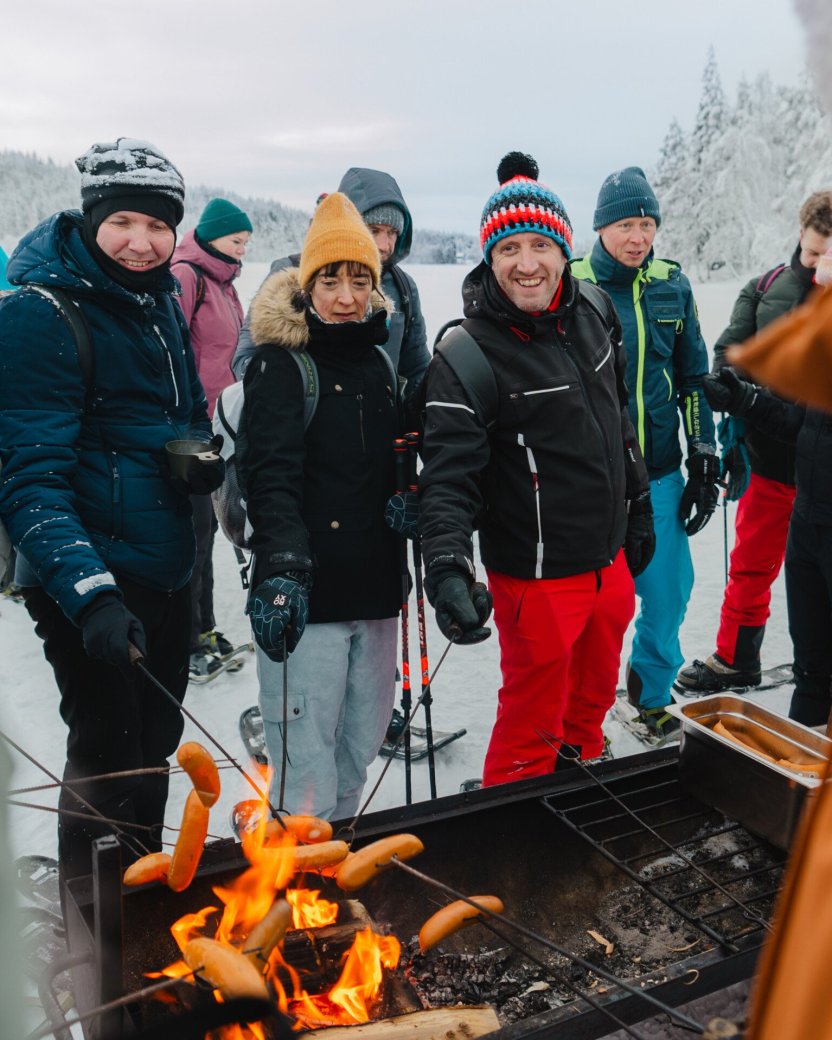 Reisgenoten braden een worst bij het vuur buiten in Lapland.