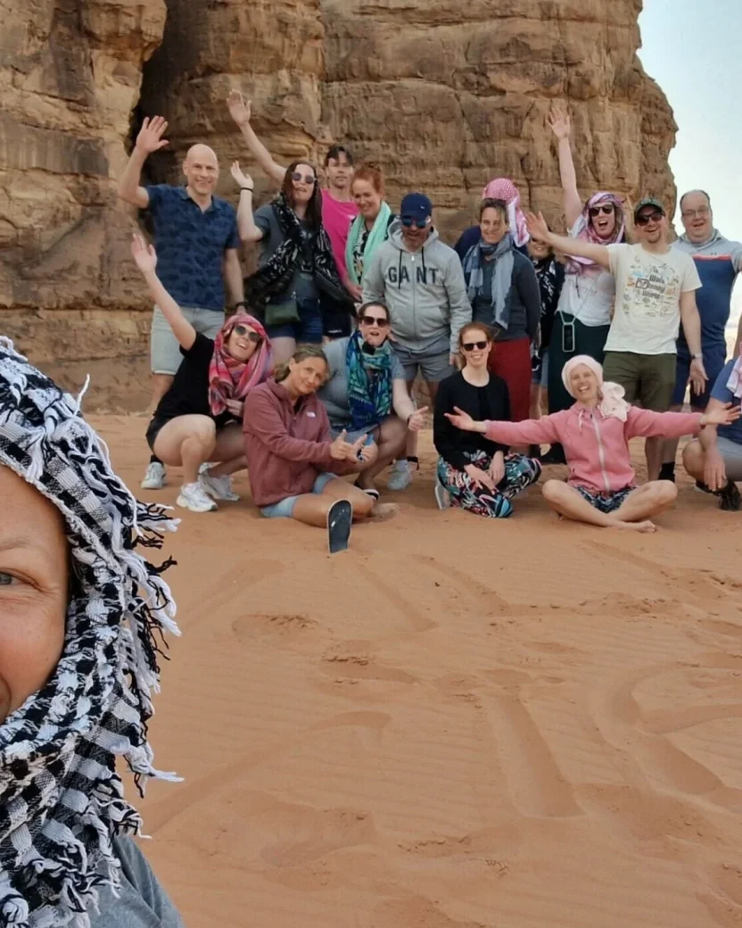 Groep reisgenoten poseert voor de foto in de woestijn in Jordanië.