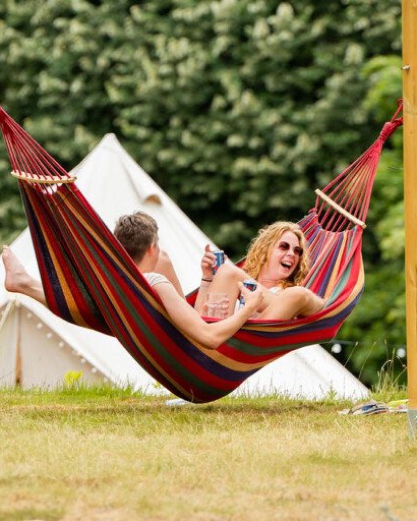Reisgenoten ontspannen samen in de hangmat op de campbase van de camping.