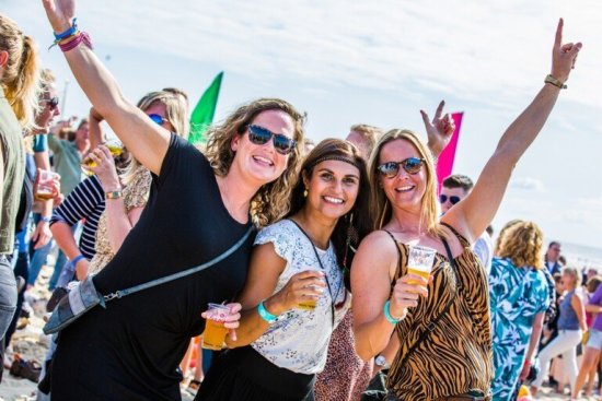 Reisgsenoten feesten op het strand met een drankje in de hand.