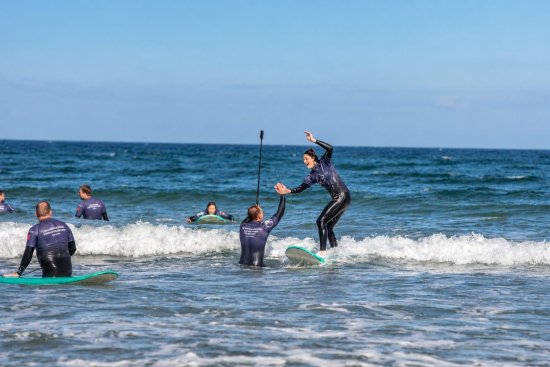 Surfer poseert op plank tijdens het leren surfen op zee.