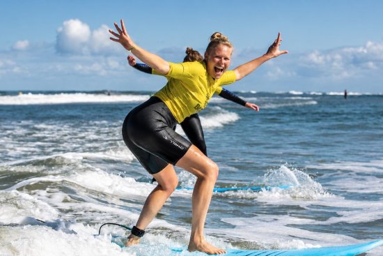 Surfer poseert op plank tijdens het leren surfen op zee.