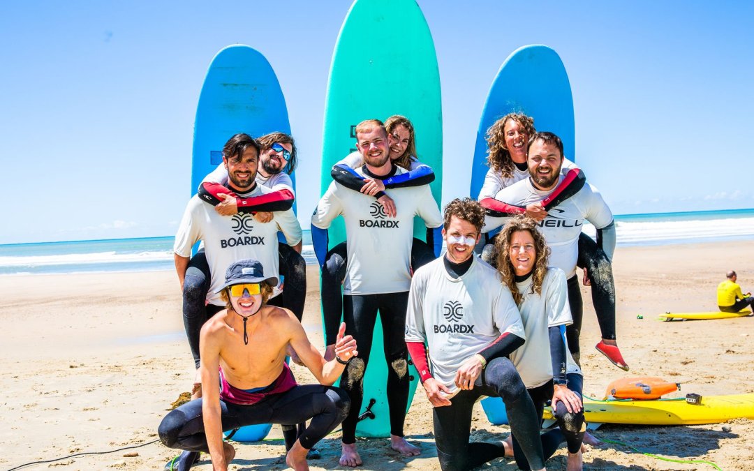 Reisgenoten poseren voor hun surfplanken op het strand.