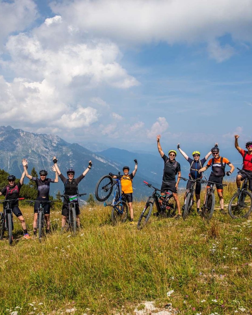 Groep mountainbikers poseren op de top van de berg in de dolomieten.