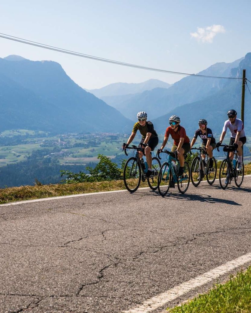 Groep reisgenoten fiets over de weg de berg op met uitzicht op de dolomieten.
