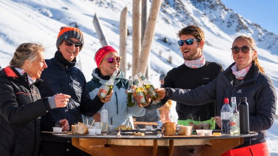 Wintersporters tijdens de apres-ski aan de piste in de zon.