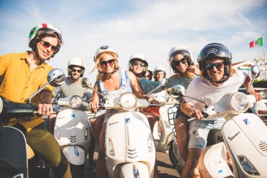 Reisgenoten poseren op vespa's tijdens de vespatour in Toscane.