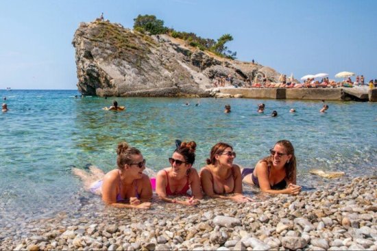 Reisgenoten liggen in het water op een kiezelstrand in Cyprus.