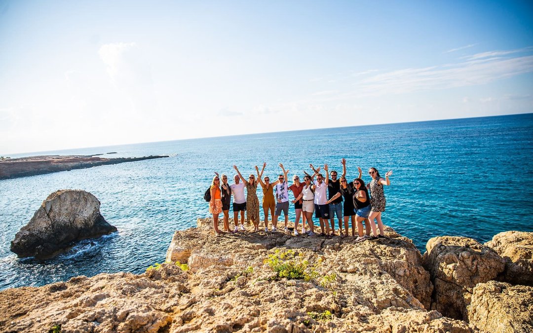 Reisgenoten poseren met elkaar op een rots voor de zee in Cyprus.