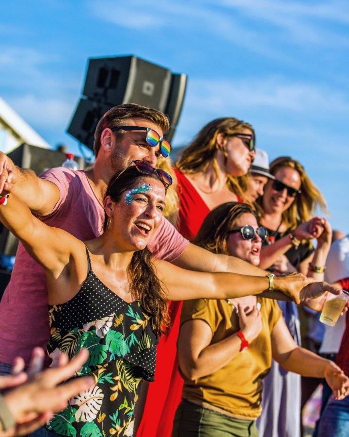 Reisgenoten feesten met elkaar in de zon tijdens een strandfeest.