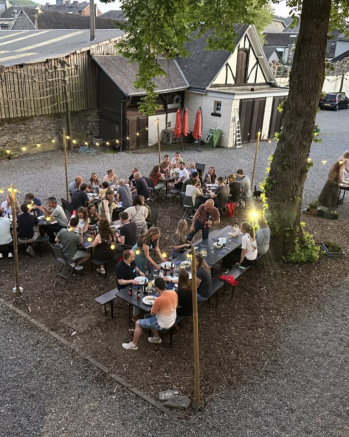 Reisgenoten dineren aan lange tafels in de ardennen.